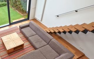 salon avec canapé en angle et escalier suspendu