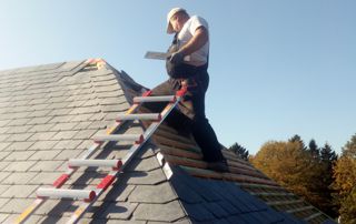 couvreur en haut d'une toiture en ardoises