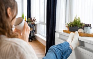 femme prenant un café les pieds sur le radiateur
