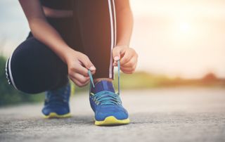 femme accroupie qui attache ses chaussures de course