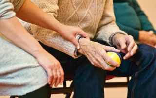 main d'une personne âgée tenant une balle