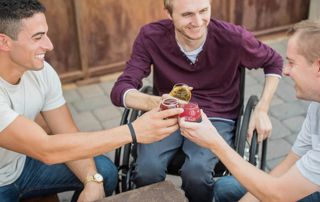 trois personnes en fauteuil roulant qui trinquent