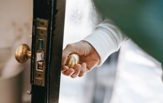 main posée sur une poignée de porte ouverte